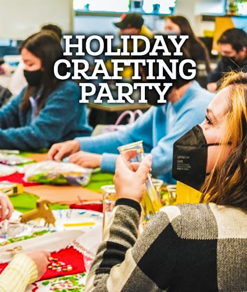 People sit at a table doing crafts for a holiday party
