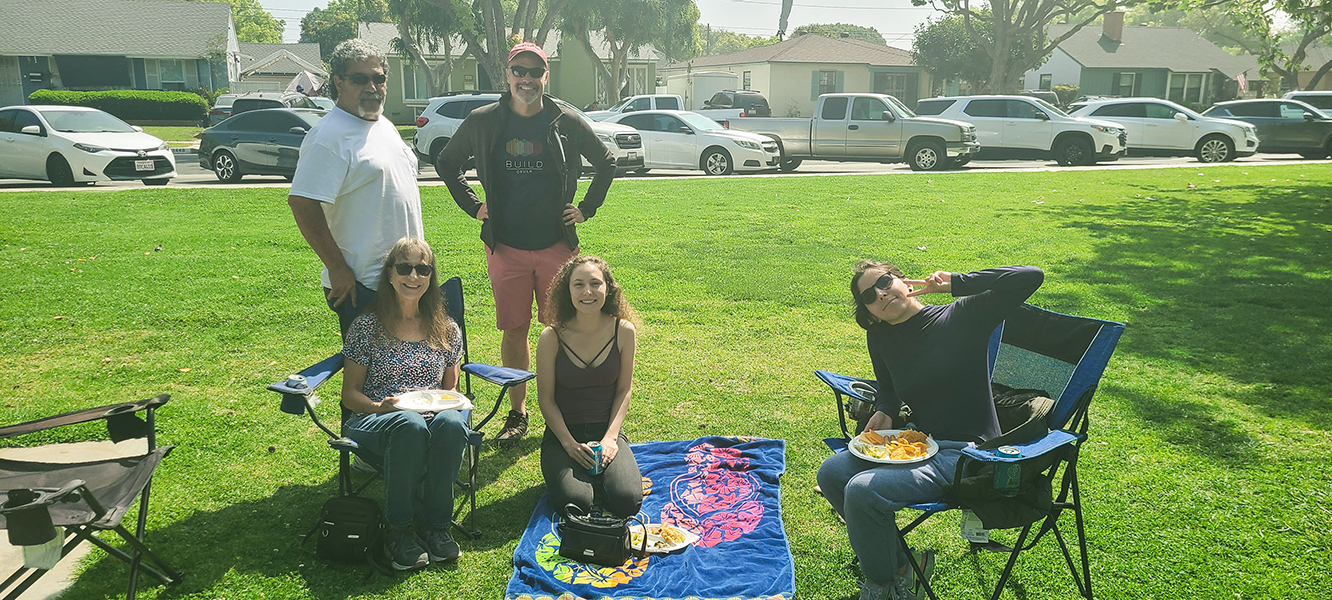 Outdoor photo with 5 people (Left  to Right): Dana De Boer’s parents, Dana, Jesse Dillon, Anna Esquivel enjoying food and chatting with each other.