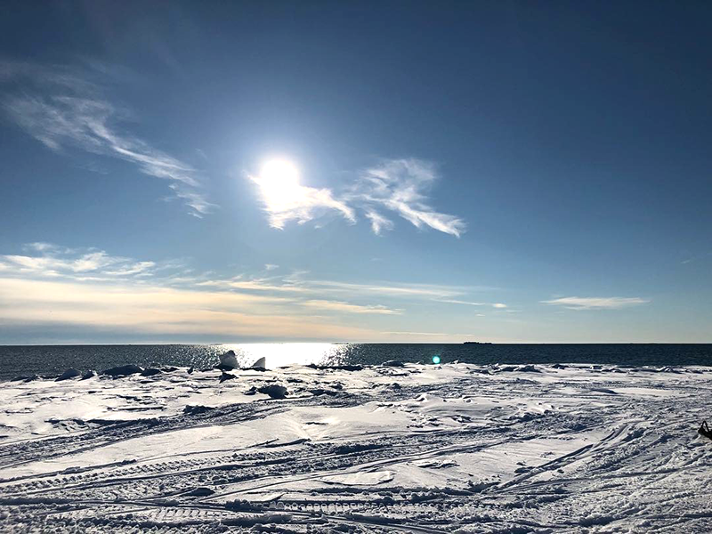 View of the Alaskan ocean seen from the edge of an icy cliff, on a sunny day